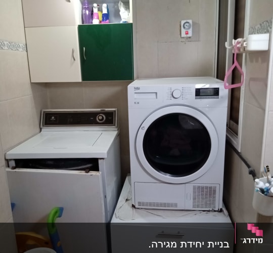 חדר כביסה עם מכונת כביסה ומייבש